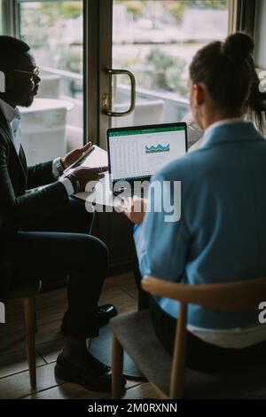 Drei Studenten sitzen und plaudern in einer Café-Bar über das neueste bevorstehende Projekt Stockfoto