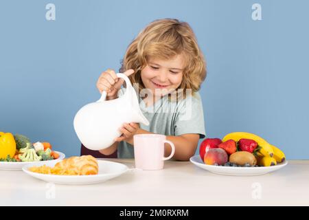 Kinder trinken Milchmilch. Ein Kind, das frühstückt und Milch eingießt. Gesundes Kind gießt Milch aus dem Krug. Stockfoto