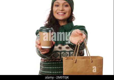 Details: Frauenhände, die Einweg-Papptasse mit heißem Tee oder Kaffee und Papierbeutel mit gelieferten frischen Speisen halten Stockfoto