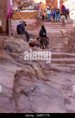 Petra, Jordanien - 3. November 2022: Esel und Menschen auf dem Weg zum Kloster, Ad Deir Trail in der berühmten antiken Stadt Stockfoto