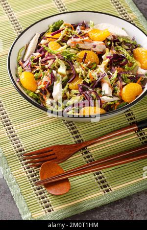 Mandarinen-Hühnchen, chinesischer Salat, Nahaufnahme auf einem Teller auf dem Tisch. Vertikal Stockfoto