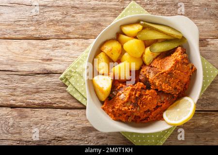 Hähnchenteile, gebacken in scharfer Sauce mit Kartoffeln, afrikanisches Hühnchen im macau-Stil, aus nächster Nähe in einem Topf auf einem Holztisch. Horizontale Draufsicht von oben Stockfoto