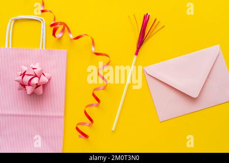 Draufsicht auf Einkaufstasche in der Nähe von Schlangenlinie und Umschlag auf gelbem Hintergrund, Stockbild Stockfoto