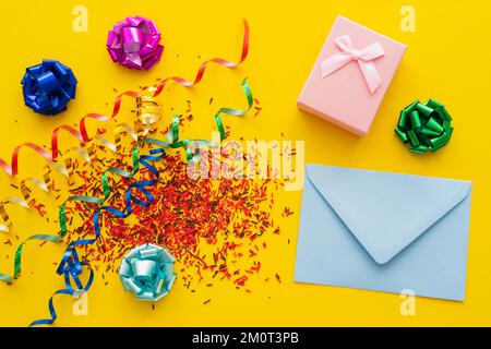 Ansicht des Umschlags in der Nähe des Geschenks und süßer Streusel auf gelbem Hintergrund, Stockbild Stockfoto