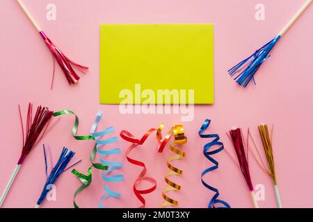 Draufsicht der leeren Grußkarte neben Schlangenhaut und Trinkhalmen mit Lametta auf rosa Hintergrund, Stockbild Stockfoto