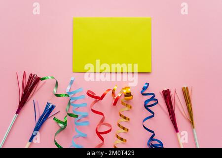 Draufsicht der leeren Grußkarte neben Trinkhalmen mit Lametta und Schlangenhaut auf rosa Hintergrund, Stockbild Stockfoto