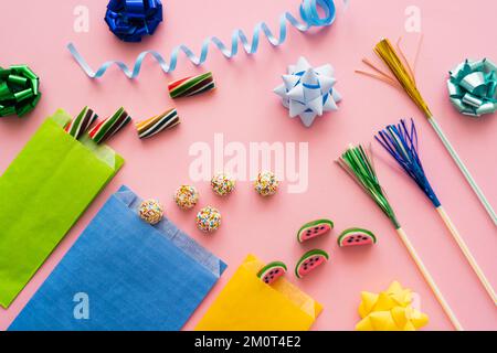 Draufsicht auf süße Süßigkeiten in der Nähe von Trinkhalmen und Geschenkschleifen auf pinkfarbenem Hintergrund, Stockbild Stockfoto