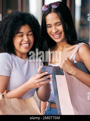 Einkaufen, Freunde und Frauen mit Telefon in der Mall genießen Freiheit, gute Zeit und gemeinsames Wochenende. Einkaufstaschen, Smartphone und junge Mädchen Stockfoto