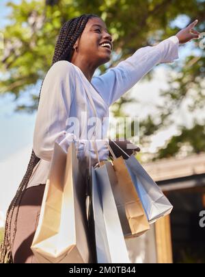 Schwarze Frau, Einkaufstüten und draußen auf der Straße, während sie glücklich war und ein Taxi oder Taxi für die Verbraucherreise suchte. Afrikanische Frau mit Stockfoto