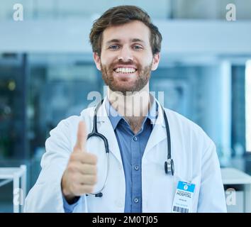 Porträt, Arzt und Daumen hoch für Erfolg in Krankenhaus, Klinik oder Gesundheitseinrichtung. Danke, Willkommen und Handgeste des selbstbewussten männlichen medizinischen Stockfoto