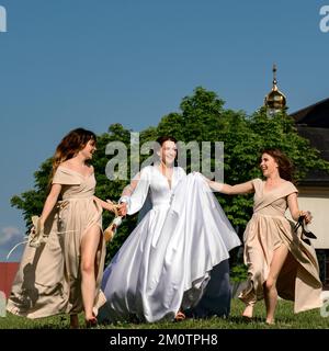 Ivano-Frankivsk, Ukraine 26. Juni 2021: Die Braut und ihre Freunde laufen barfuß auf dem Gras, Morgen der Braut mit ihren Freunden, Vorbereitung auf die Stockfoto