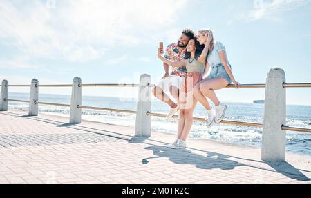 Sagen Sie Cheese. Aufnahme einer vielfältigen Gruppe von Freunden in voller Länge, die zusammen stehen und ein Mobiltelefon verwenden, um im Freien Selfies zu machen. Stockfoto