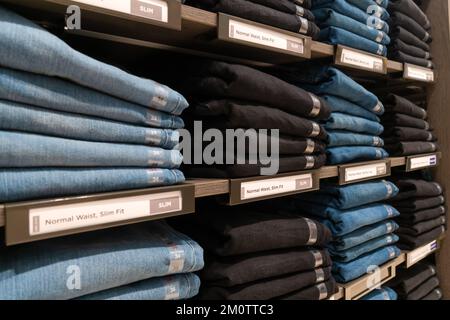 Nahaufnahme von vielen Jeans in den Regalen im Laden. Ein Haufen Jeans auf dem Regal. Konzept des Einkaufs, Verkaufs, Einkaufs und Jeans. Stockfoto