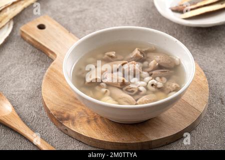 Four Tonics Suppe. Köstliches hausgemachtes taiwanesisches traditionelles chinesisches Kräutergericht mit Kräutern, Schweinedärm auf grauem Tischhintergrund Stockfoto