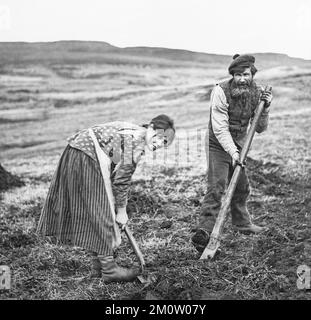 Alate 19. Century Schwarzweißfoto, aufgenommen auf der Isle of Skye, zeigt einen Mann und eine Frau mit einem traditionellen schiefen Spaten namens Cas Chrom. Stockfoto