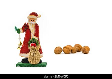 Weihnachtsmann Holzfigur und Walnüsse, die als Studioaufnahmen auf weißem Hintergrund ausgeschnitten wurden, um sie als Vorlage zu verwenden Stockfoto