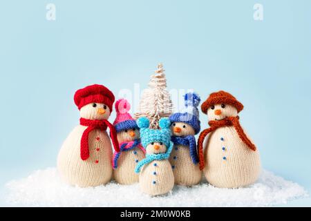 Gestrickte Schneemänner in farbenfrohen Mützen und Schals auf blauem Hintergrund. Das Konzept von Weihnachten, Neujahr und Wintermärchen. Flach verlegt Stockfoto