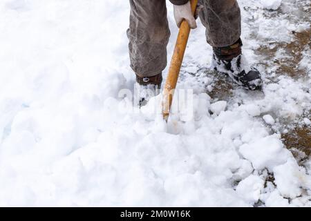 Ein Mann entfernt Schnee mit einer Schaufel an einem Wintertag nach einem schweren Schneefall. Selektiver Fokus. Stockfoto