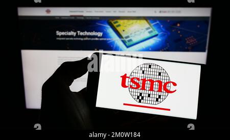 Person, die ein Mobiltelefon mit dem Logo der Taiwan Semiconductor Manufacturing Company (TSMC) auf dem Bildschirm vor der Webseite hält. Konzentrieren Sie sich auf das Display des Telefons. Stockfoto