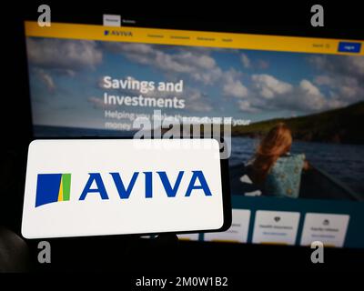 Person, die ein Smartphone mit dem Logo der britischen Versicherungsgesellschaft Aviva plc auf dem Bildschirm vor der Website hält. Konzentrieren Sie sich auf das Display des Telefons. Stockfoto