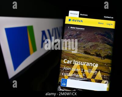 Person mit Smartphone und Website der britischen Versicherungsgesellschaft Aviva plc auf dem Bildschirm vor dem Logo. Konzentrieren Sie sich auf die Mitte des Telefondisplays. Stockfoto