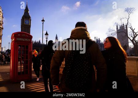 Touristen stellen sich an, um bei sonnigem Wetter in London mit einer roten Telefonzelle am Parliament Square in Westminster Fotos zu machen. Das MET-Büro hat in den kommenden Tagen eine Reihe von Wetterwarnungen für Schnee und Eis in Teilen Schottlands, Nordirlands, Wales, der Ostküste und Südwestenglands herausgegeben. Foto: Donnerstag, 8. Dezember 2022. Stockfoto