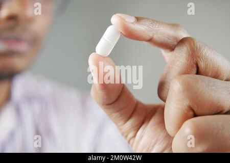 Junge Männer, die eine einzige medizinische Pille in der Hand haben Stockfoto