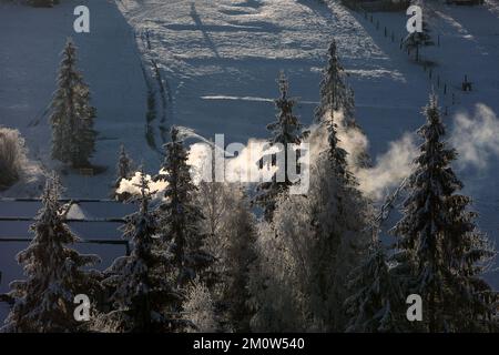 REGION IVANO-FRANKIVSK, UKRAINE - 30. NOVEMBER 2022 - an einem winterlichen Morgen, Ivano-Franki, erhebt sich der Rauch bei Sonnenaufgang aus einem Schornstein in den Karpaten Stockfoto