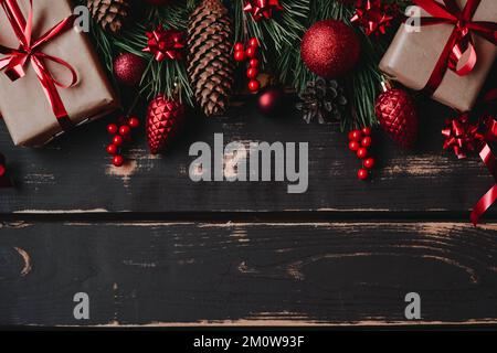 Christmass flache Geschenkboxen, rotes weihnachtsbaumspielzeug, weihnachtsdekoration und Fichtenbranz auf Holzhintergrund. Stockfoto