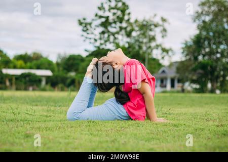 Kindermeditation mit Yoga-Pose auf grünem Grasfeld. Aktivitäten im Freien für Kinder, Yoga-Übungen, Kinder können lernen, wie man trainiert. Stockfoto