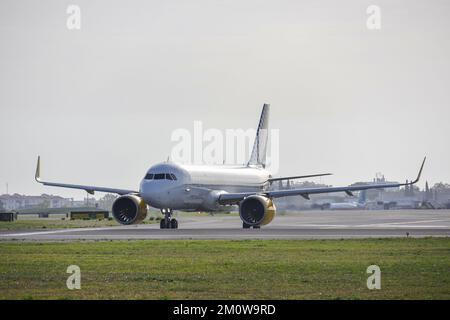 Ein Flugzeug des Typs Airbus A320-271N der Fluggesellschaft Vueling, am Flughafen Lissabon bei Sonnenaufgang, umgeben von einem grünen Rasen Stockfoto