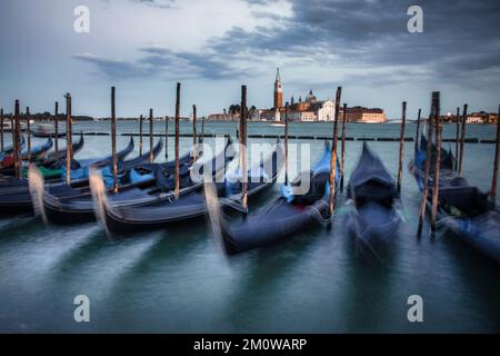 Die Gondelbahn parkt am Ufer der Markusplatz mit der Insel Saint Georgio Maggiore im Hintergrund im historischen Venedig, Italien. Stockfoto