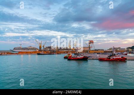 Ancona, Italien - 24. November 2022: Industriehafen von Ancona bei Sonnenaufgang mit Schiffen der Küstenwache und Kreuzfahrtschiffen im Bau in den Werften Stockfoto