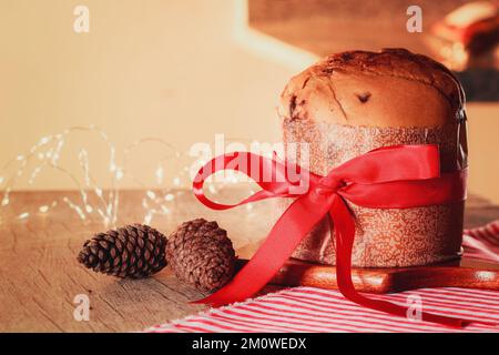 Kuchen mit Obst und Schokoladenchips auf einem Holztisch, dekoriert zu Weihnachten. Selbst gemachtes Weihnachtsbrot auf gelbem Hintergrund, Kopierbereich. Stockfoto