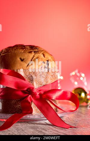 Kuchen mit Obst und Schokoladenchips auf einem Holztisch, dekoriert zu Weihnachten. Selbst gemachtes Weihnachtsbrot auf rotem Hintergrund, Kopierbereich. Stockfoto