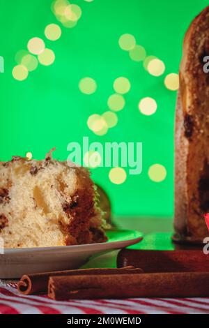 Kuchen mit Obst und Schokoladenchips auf einem Holztisch, dekoriert zu Weihnachten. Selbst gemachtes Weihnachtsbrot auf grünem Hintergrund, Kopierbereich. Stockfoto