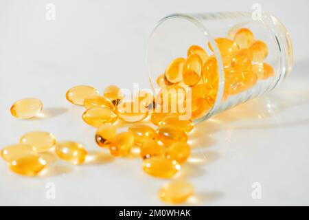 Fischöl Omega 3 Pillen Kapseln in einer Glasflasche auf weißem Marmorhintergrund, gesunde Ernährung, Nahrungsergänzungsmittel, Vitamine D. Stockfoto