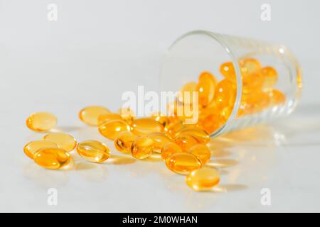 Fischöl Omega 3 Pillen Kapseln in einer Glasflasche auf weißem Marmorhintergrund, gesunde Ernährung, Nahrungsergänzungsmittel, Vitamine D. Stockfoto