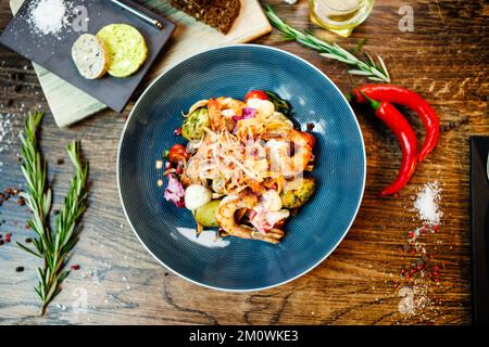 Warmer Salat mit argentinischen Königsgarnelen. Mandelkartoffel, Mini-Romana-Salat, Karotten, Kirschtomaten, Pesto, Schwarze Wurzelchips, karamellisierte Walnüsse, Rüben Stockfoto