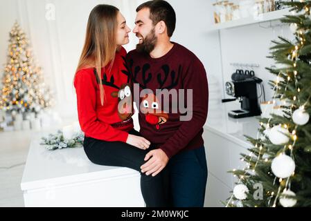 Ein attraktives Paar öffnet seine Weihnachtsgeschenke in der Nähe des Weihnachtsbaums Stockfoto