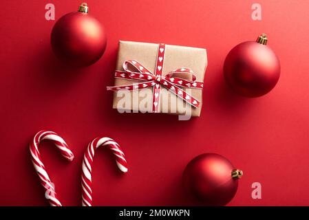 Weihnachtsgeschenke verpackt aus Kraftpapier dekorierte Schleife und Tannenzweige auf marsala-rotem Hintergrund. Flach liegend, Draufsicht. Weihnachten, Winter Stockfoto