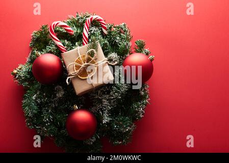 Weihnachtsgeschenke verpackt aus Kraftpapier dekorierte Schleife und Tannenzweige auf marsala-rotem Hintergrund. Flach liegend, Draufsicht. Weihnachten, Winter Stockfoto