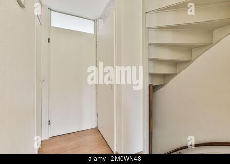 Weißer Flur mit Treppe, der in die zweite Etage des modernen Apartments mit minimalistischem Innendesign führt Stockfoto