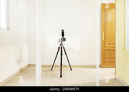 Eine selbstfotografierte Kamera mit Stativ und Blitz an einer Spiegelschiebetür eines integrierten Kleiderschranks Stockfoto