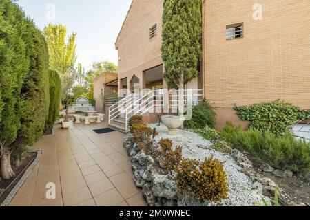 Innengärten im Innenhof eines Einzelhauses mit Hecken, Töpfen und Bäumen neben einer Treppe Stockfoto