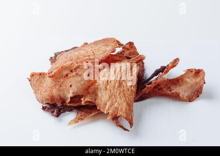 Trockenfleisch-Stücke isoliert auf weißem Hintergrund. Rinderjerky auf einem Holzbrett, Draufsicht. Rinderscheiben-Dörrfleisch. Hochwertiges Foto Stockfoto