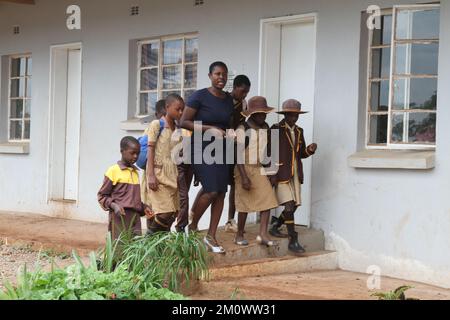 Goromonzi, Simbabwe. 7.. Dezember 2022. Eine Lehrerin geht mit ihren Schülern vor einem Klassenzimmer an der Vhuta-Grundschule im Bezirk Goromonzi, Simbabwe, 7. Dezember 2022. Ein chinesisch investiertes Unternehmen hat im Rahmen seiner Initiativen zur sozialen Verantwortung der Unternehmen zwei Klassenzimmer und Möbel an eine örtliche Schule übergeben, um die lokale Bildung zu verbessern. ZU „Feature: Chinesisches Unternehmen spendet Klassenräume an die simbabwische Schule“. Guthaben: Tafara Mugwara/Xinhua/Alamy Live News Stockfoto