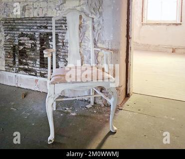 Leerer Vintage-Stuhl in einem renovierungsbedürftigen Zimmer Stockfoto
