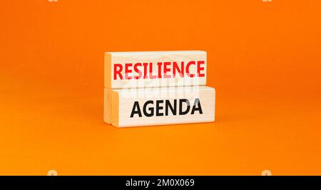 Symbol für Resilienz-Agenda. Konzeptwort „Resilience Agenda“ auf Holzblöcken getippt. Schöner orangefarbener Tischhintergrund. Unternehmen und Widerstandsfähigkeit Stockfoto