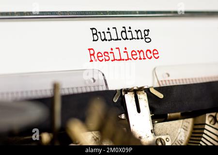 Das Symbol für Resilienz aufbauen. Das Konzeptwort „Resilienz aufbauen“ wurde auf eine alte Schreibmaschine geschrieben. Wunderschöner weißer Hintergrund. Business und Gebäudewohnung Stockfoto